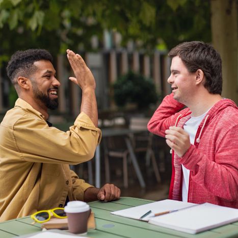 Someone with a disability high-fiving a friend/mentor