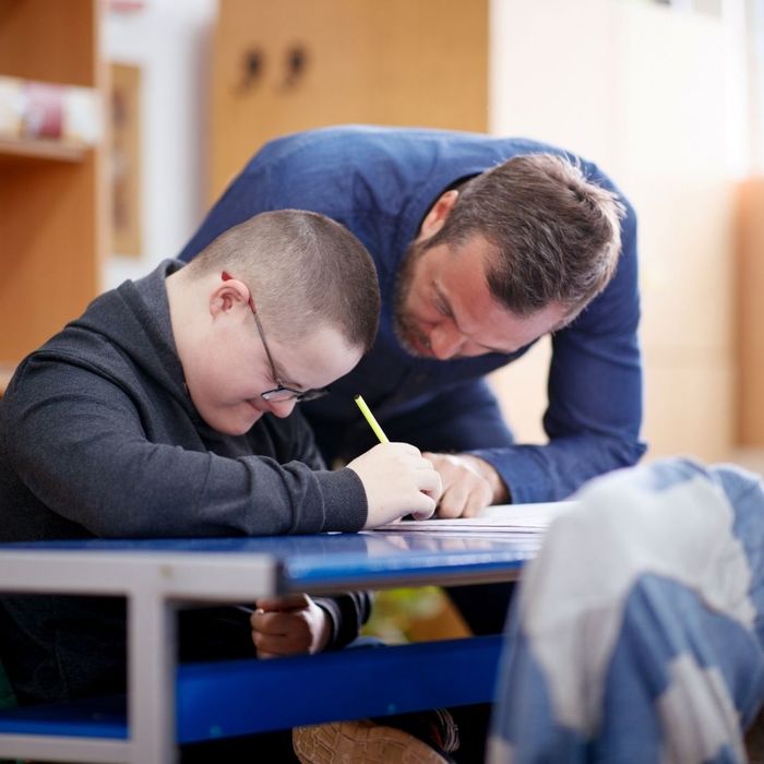 An adult assisting a man with down syndrome with a job application