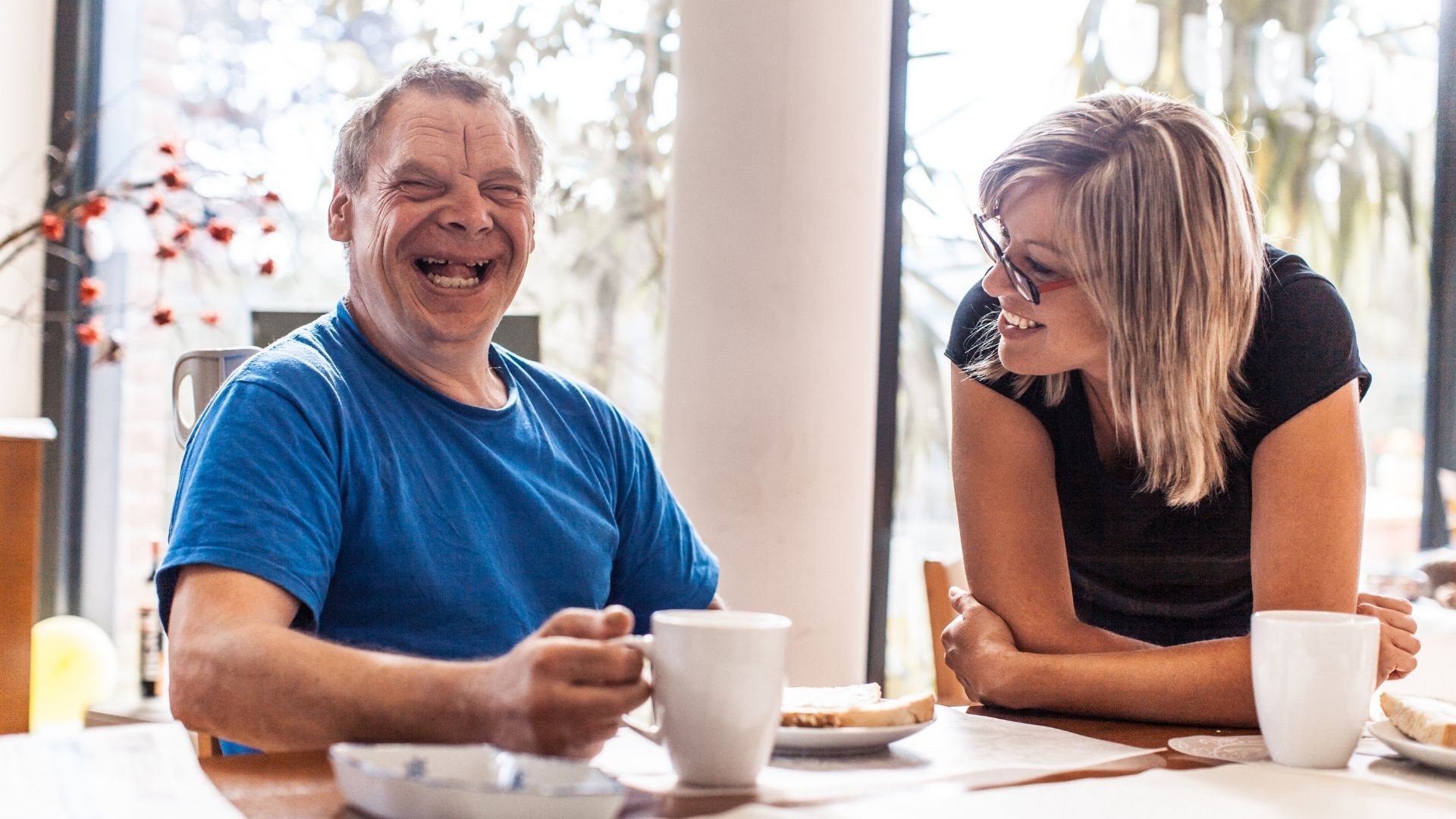 Adult with disabilities laughing with a caretaker